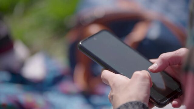 Mano de mujer usando tel&eacute;fono celular al aire libre