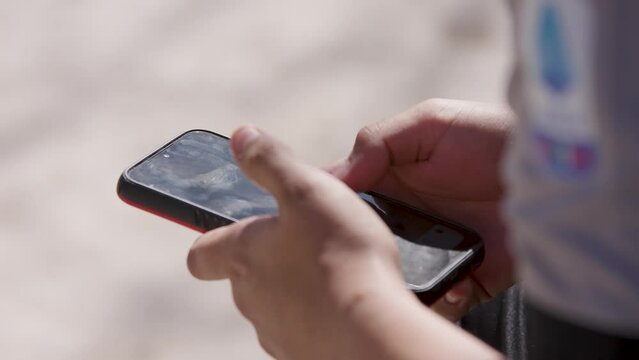 Mano usando tel&eacute;fono celular al aire libre