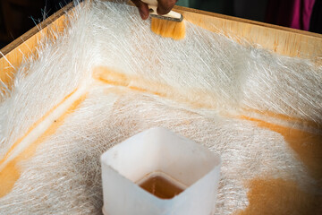 Brushing solution through fiberglass sheets on a wooden box. A diy project at home.