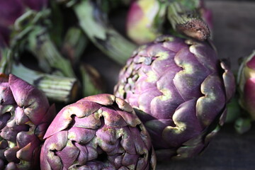 four artichokes next to one another with purple colored petals
