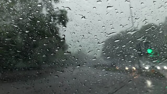 POV of rain falling on windshield of car while driving in Hong Kong