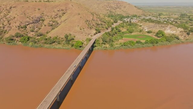 Car crossing the long bridge above Tsiribihina River in Madagascar countryside. Dirty river with yellow color after soil erosion.