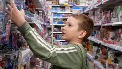 Close-up of a cute boy taking a toy from the stand of a toy shop