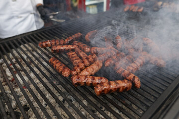 Romanian traditional mici (mititei), grilled ground meat rolls in cylindrical shape on the barbecue grill.