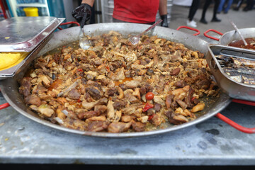Romanian traditional meat stew being cooked in a huge pan at an outdoor food festival.