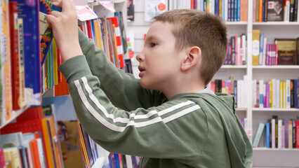 Close-up of a cute boy choosing a book in a book shop or library