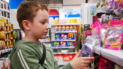 Close-up of a cute boy looking at the toy in his hands in a toy shop