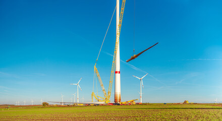 Building and assembling a construction windturbine by Crawler Track Crane - machinery. Farmland...