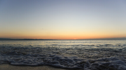 Obraz premium Sunset by the shore. Waves crashing into fine white sand during golden hour