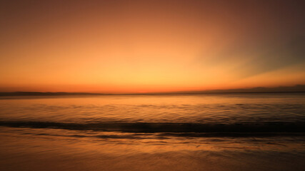 Naklejka premium Sunset by the shore. Waves crashing into fine white sand during golden hour