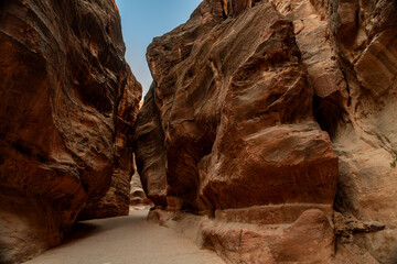 View of the narrow Siq canyon pathway leading to Petra, Jordan, with towering sandstone cliffs.