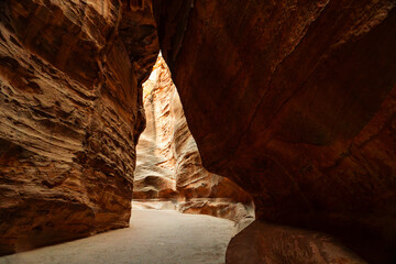 View of the narrow Siq canyon pathway leading to Petra, Jordan, with towering sandstone cliffs.
