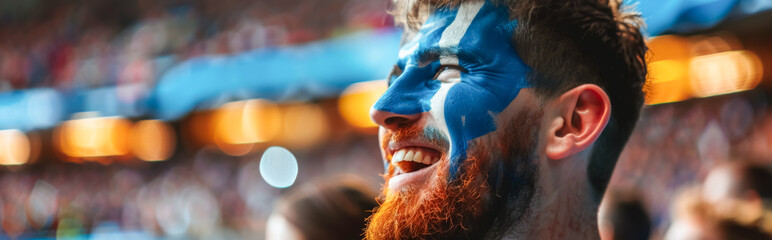 Happy Scottish male supporter with face painted in Scottish flag, Scottish male fan at a sports event