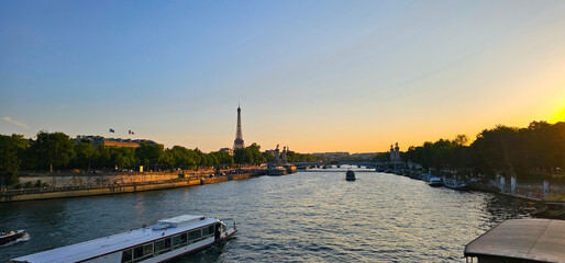 View of the River Seine at sunset on a summer day with the Eiffel Tower in the distance, clear blue...