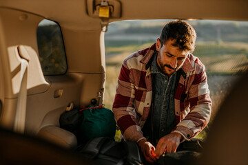 Outdoor enthusiast in his vehicle, geared up with a backpack for a trek across golden hills