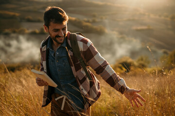 Adventurous man hiking through golden hills with a backpack on a sunny day