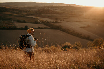 Traveler walking along scenic golden hills, carrying a backpack