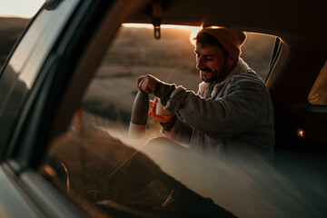 A young male backpacker having a travel break while relaxing in his van