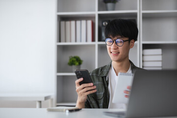 Young Asian student boy in private clothes studying online with laptop at home.