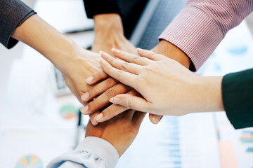 Fototapeta premium Close-up top view of young business team people putting their hands together background with business graph