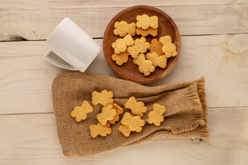 Delicious cookies in the shape of a bear with a jute bag on a wooden table, top view, macro.