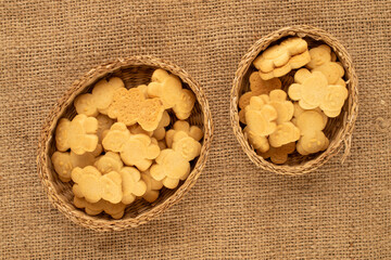 Delicious cookies in the shape of a bear with a straw dish on a jute cloth, top view, macro.