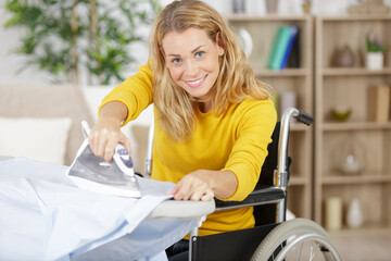 happy young woman in wheelchair during ironing at home