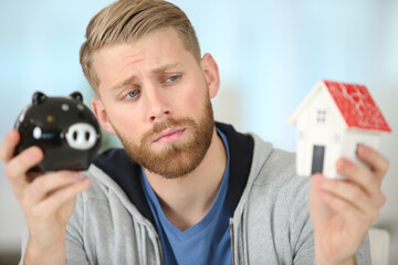 confused man holding piggy bank with serious face
