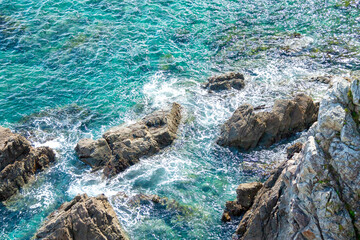 透明度の高い海の岩礁に打ち寄せる波