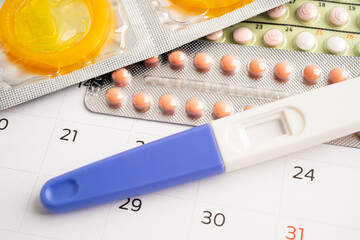 Pregnancy test and birth control pills on calendar, contraception health and medicine.