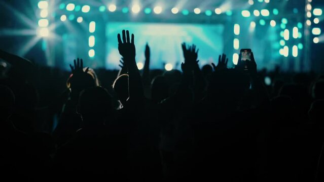 Young Christian youths are raising their hands to sing praises and worship God. Music festivals, crowds of people, and taking videos with their phones.