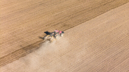 Tractor working in agriculture fields, aerial drone view