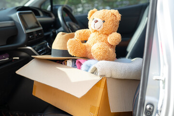 Volunteer provide clothing donation box with used clothes and doll in car to support help for...