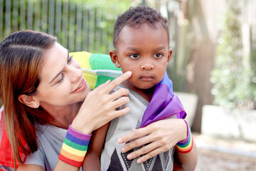 Happy homosexual lesbian woman and her adopted child with rainbow flag. Young beautiful girl and...