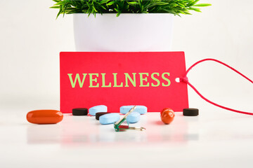 Wellness sign on a red card on a white background with pills, vitamins in the foreground