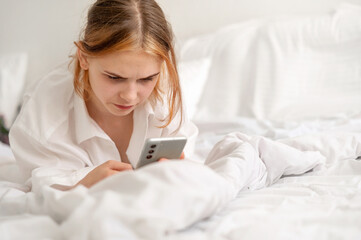 Serious bored young girl with gloomy face expression looking at smartphone screen, teenager using...