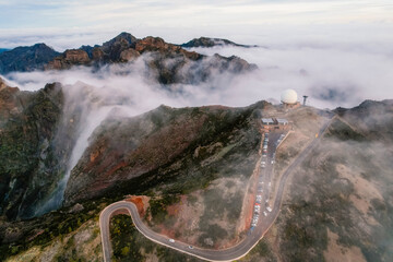 Aerial view of majestic mountain ridges at sunrise with falling fog from top of Pico do Areeiro,...