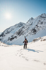 Fototapeta na wymiar Mountaineer backcountry ski walking ski alpinist in the mountains. Ski touring in alpine landscape with snowy trees. Adventure winter sport. High tatras, Slovakia