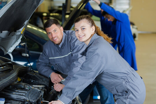 portrait of a young female trainee auto-mechanic with her supervisor