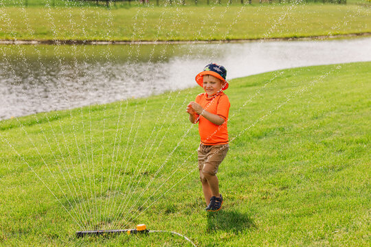 Joyful child playing in sprinkler on sunny day