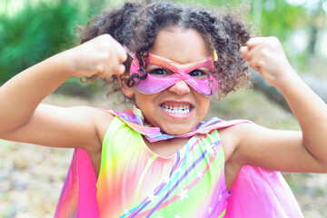 Excited child in colorful superhero costume showing strength ou
