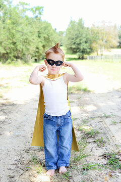 Toddler in superhero costume posing confidently outdoors.