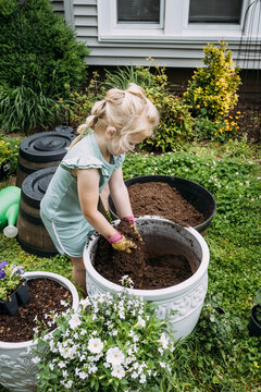 Little gardener helping pot spring flowers in potting soil