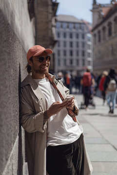 Smiling man with a phone on a city street.