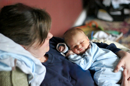 Mother holding her sleeping newborn baby at home