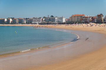 Dia Ensolarado na Praia de Saint Jean de Luz com alguns banhistas  na praia e turistas na cidade ao...