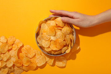 Potato chips in a bowl on a yellow background