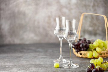 Grape vodka or grappa. Strong alcoholic drink in grappa glasses on the table. Fresh grapes