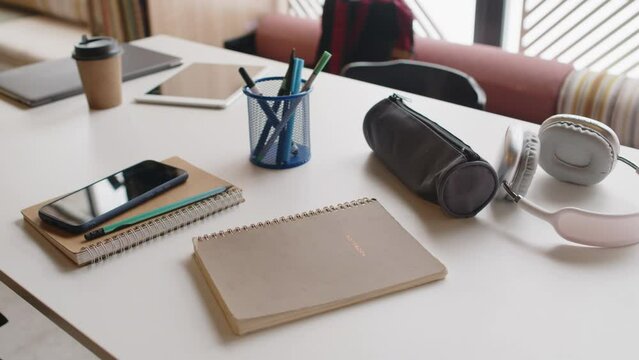 Close up no people shot of copybooks, mobile phone, pencil case and digital tablet on desk in school library