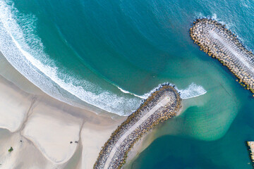 Aerial zenithal view of a groyne on a beach, breakwater for harbor protection